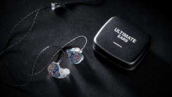 An in-ear monitor rests on a surface next to a case branded "Ultimate Ears"
