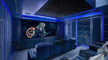 A home theater is illuminated in dark blue, with action on-screen and two visible rows of seats.