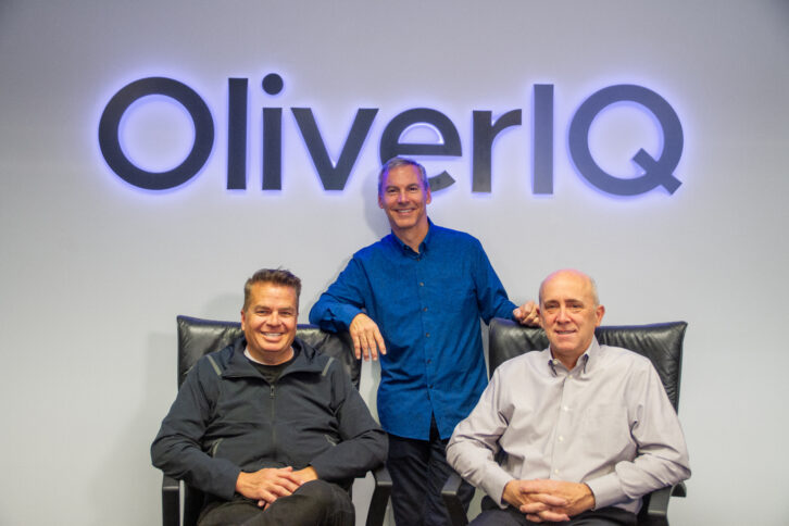 Image of the OliverIQ company leadership in front of the OliverIQ logo.